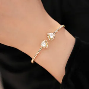 Elegant gold open cuff bracelet with two heart-shaped crystals and pavé settings