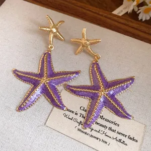 Close-up detail of vintage purple enamel starfish drop earrings on rustic background