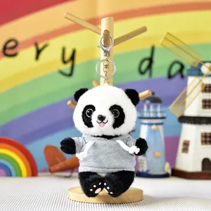 Close-up of a cute panda plush keychain wearing a grey hoodie on a wooden stand