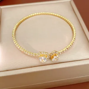 Close-up of golden open bangle with heart-shaped crystals and sparkling rhinestones