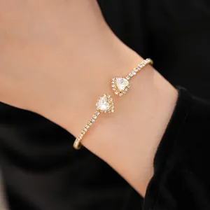 Close-up view of an elegant gold heart open bracelet with shimmering crystals