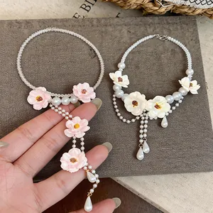 Dettaglio di eleganti collane di perle in stile francese con fiori e ciondoli a goccia