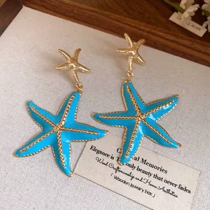 Detailed view of blue starfish dangle earrings with gold finish and silver needles
