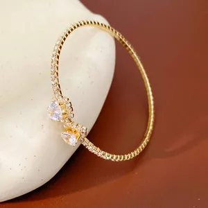 Macro detail of a luxurious gold-plated open bangle bracelet with twin heart-shaped crystals