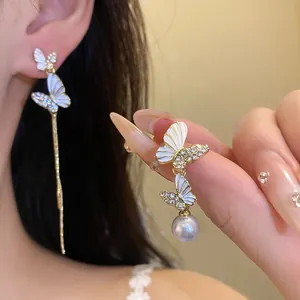 Primer plano de elegantes pendientes de mariposa asimétricos con perla y diamantes