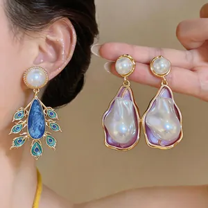 Detailed macro view of palace-style irregular pearl and peacock motif earrings.