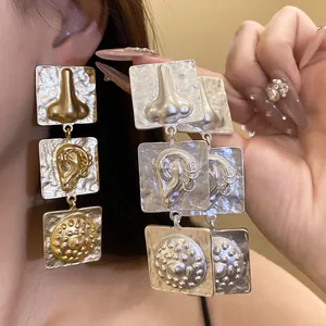Close-up of retro square tiered drop earrings with textured human organ motifs.
