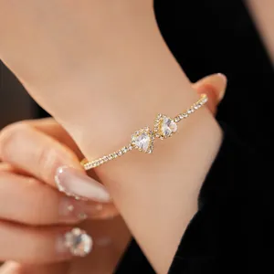 Detail shot of a gold heart diamond open bangle bracelet on a female wrist
