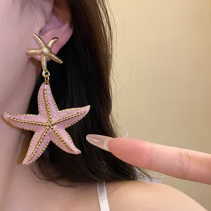 Detailed close-up of pink starfish pendant earring featuring golden oil-dripping texture