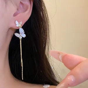 Vista detallada de elegantes pendientes largos de mariposa con esmalte y pedrería