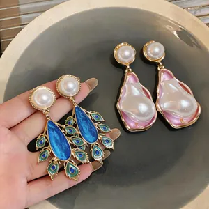 Close-up of vintage palace style peacock enamel and pink pearl teardrop earrings