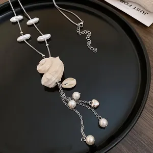 Detailed view of sea shell pendant necklace featuring pearls and a silver heart charm