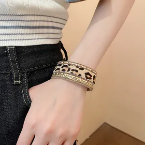 Close-up view of a bohemian multi-layer leopard print magnetic leather bracelet on a wrist