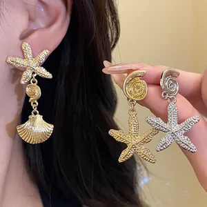 Close-up of golden and silver starfish and shell dangle earrings on a model