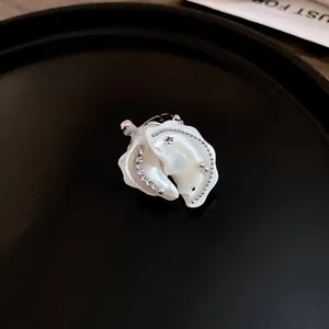 Macro view of a unique pearl and shell-shaped necklace pendant with silver beads.