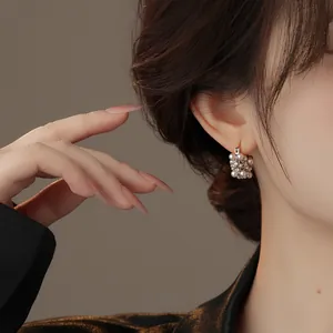 Close-up of elegant French vintage pearl hoop earrings with rhinestones on a model.
