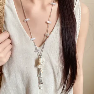 Detail view of vacation style necklace with pearls and a shell conch pendant on model