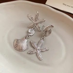 Detailed view of silver sea shell and starfish drop earrings with textured surface.