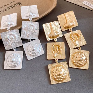 Close-up of vintage gold and silver embossed square dangle earrings with art details