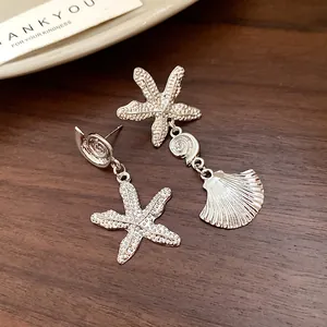 Detailed view of silver starfish and seashell drop earrings on a wooden background.