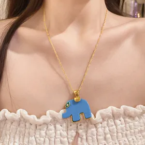 Close-up of a blue resin elephant pendant necklace worn by a model in a white top