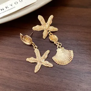 Detailed close-up of elegant gold-tone asymmetric starfish and textured shell drop earrings