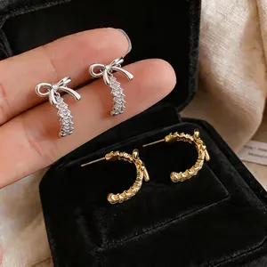 Elegantes pendientes de aro en forma de lazo de plata y oro en un joyero