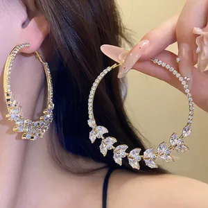 Detailed close-up of large gold hoop earrings with sparkling zircon wheat ear design