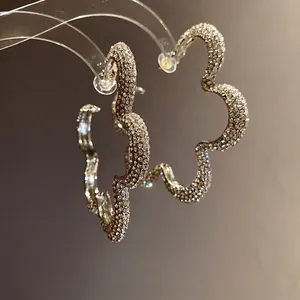 Elegant silver-toned flower hoop earrings fully paved with glittering rhinestones for women.