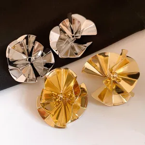 Detailed view of oversized geometric pleated fan-shaped stud earrings in gold and silver