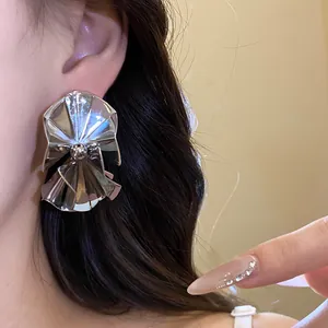 Detailed close-up showing vintage silver-tone sculptural metallic earrings worn by a model