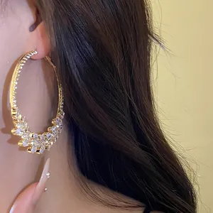 Close-up detail of a golden circular hoop earring featuring a shimmering zircon wheat ear design