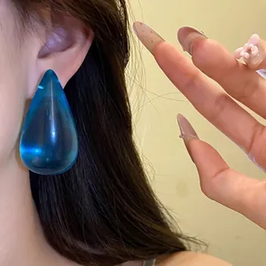 Eleganti orecchini a goccia in resina blu traslucida con perno in argento sulla pelle