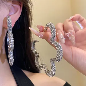 Detailed macro view of oversized flower-shaped hoop earrings with sparkling rhinestones