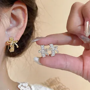 Primer plano de elegantes pendientes en forma de C con lazo calado en oro y plata