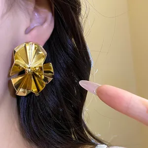 Detailed view of vintage golden pleated fan-shaped stud earrings with a shiny metallic finish