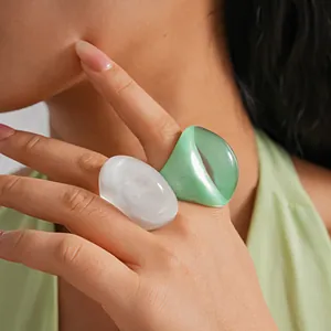 Close-up detail of vintage oversized white and green chunky resin rings on model's hand