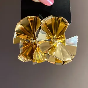Close-up of elegant golden pleated fan-shaped stud earrings with high-gloss finish