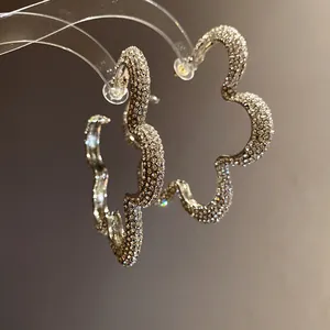Detailed view of flower-shaped hoop earrings encrusted with sparkling crystals.