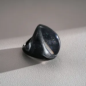 Macro view of an exaggerated dark resin fan-shaped ring with galaxy shimmer effect