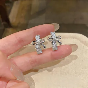 Detalle macro de pendientes de botón en forma de C plateados con diseño de lazo de encaje hueco