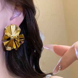 Detailed close-up showing retro gold pleated fan-shaped stud earrings worn on model ear