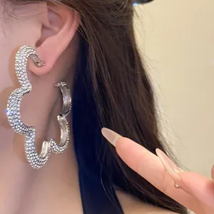 Detailed view of elegant sparkling rhinestone flower hoop earrings worn by a model.