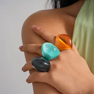 Close-up view of vibrant chunky resin rings worn by a model for a statement look