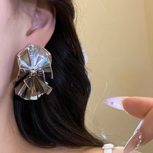 Detailed close-up showing a large silver pleated fan-shaped earring on a woman's ear