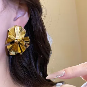 Detail view of vintage gold metallic fan-shaped stud earrings on a model's ear