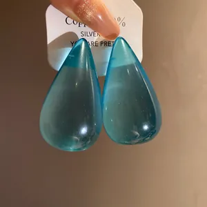Dettaglio ravvicinato di orecchini a goccia in resina blu con perno in argento puro.