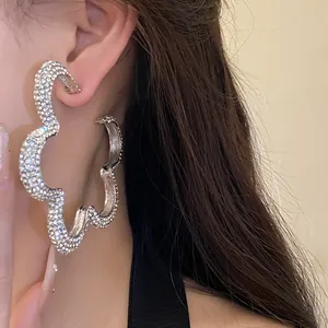Detailed view of oversized silver flower earrings with sparkling rhinestone crystals