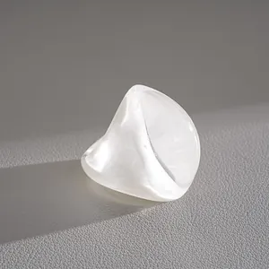 Macro view of a white resin fan-shaped ring showing pearlescent texture and shadow