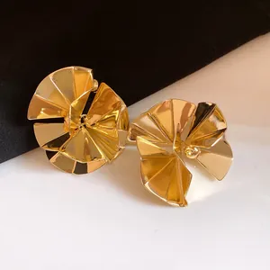 Macro view of gold fan-shaped geometric earrings with a vintage minimalist finish
